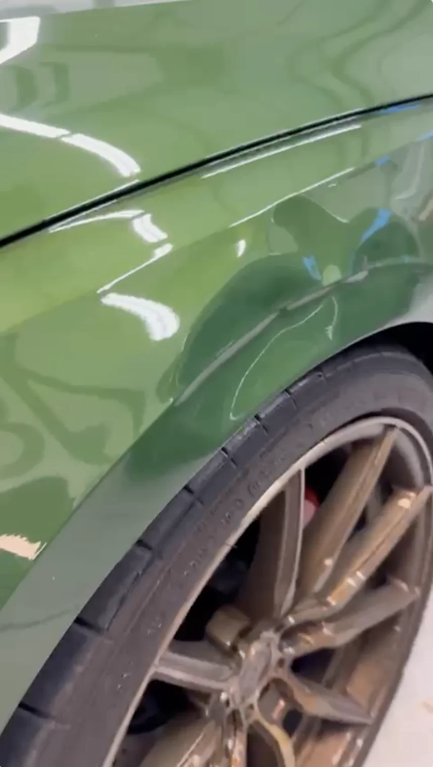 Before — green car fender dent